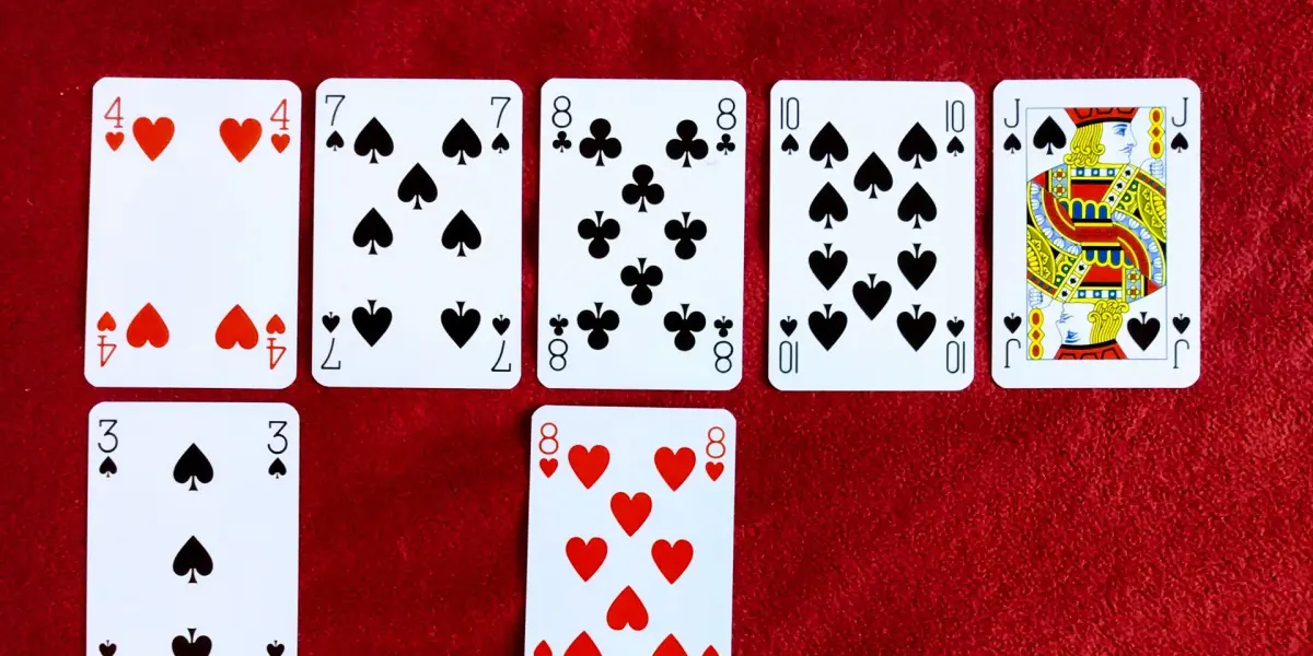 Playing cards laid out in rows on red felt
